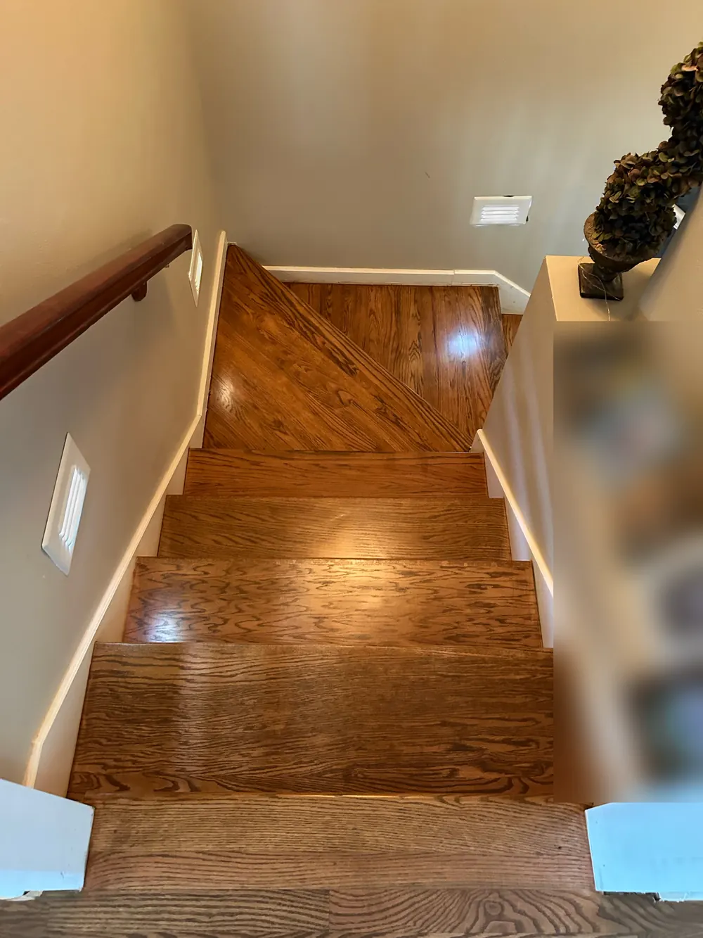 Looking down a stained oak staircase to a landing where the boards are laid on the diagonal