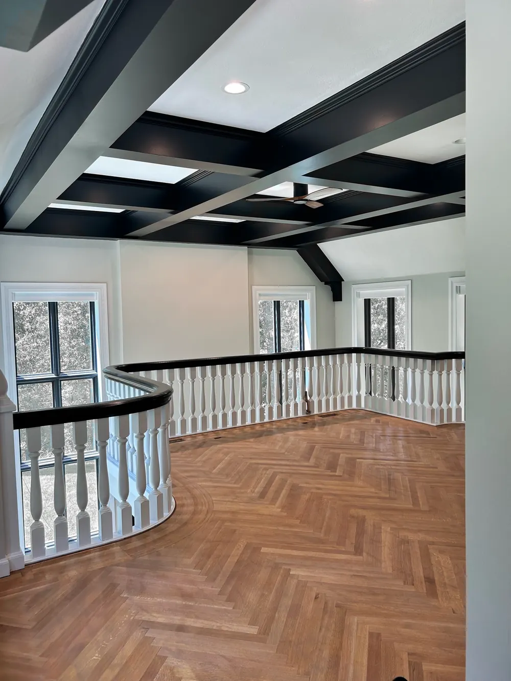 Herringbone oak on an upstairs landing, with a border following a curved white balustrade