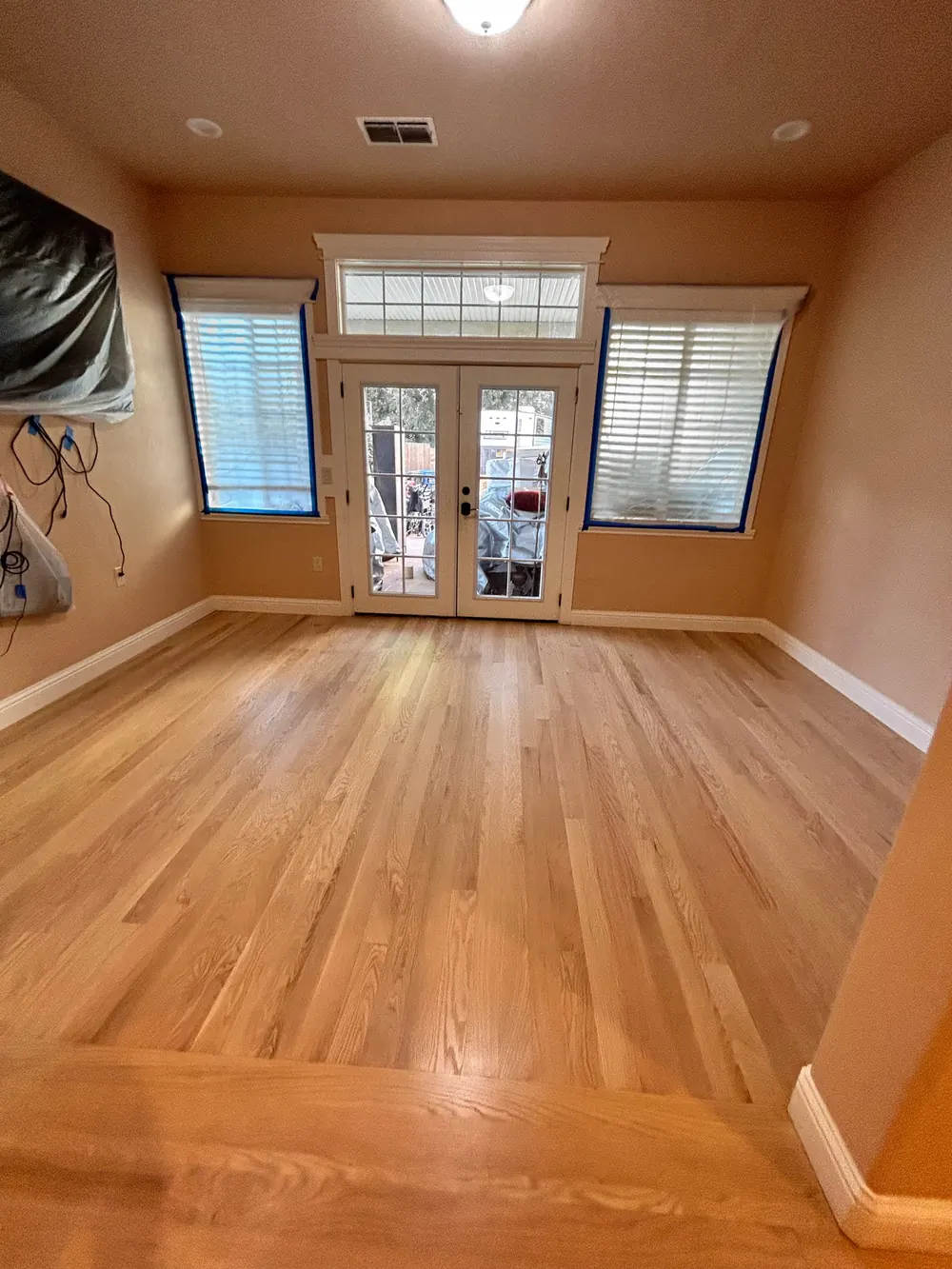 Natural red oak floor in a room facing French doors and two windows