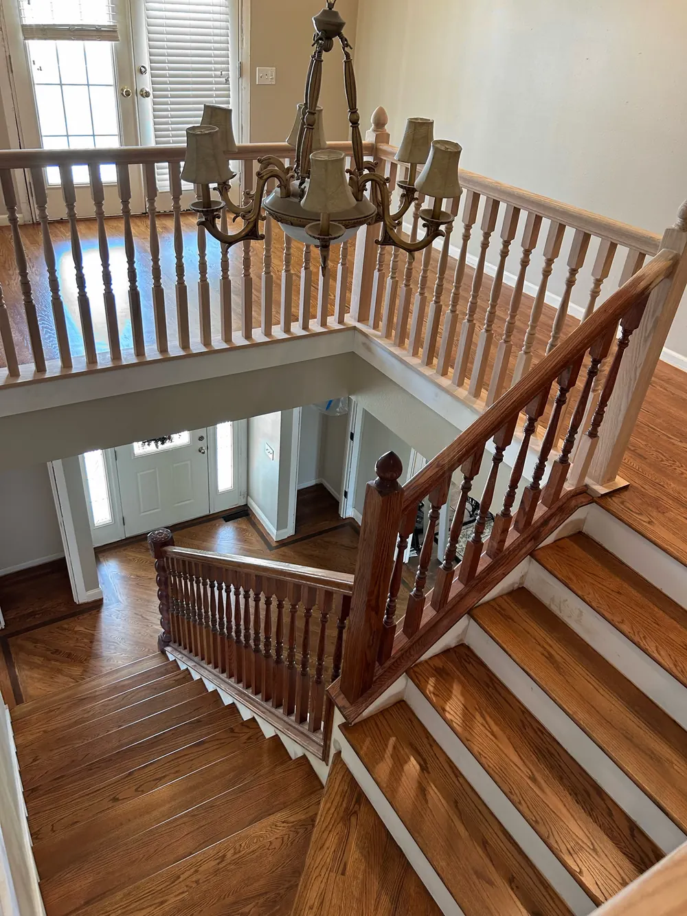 An open staircase with amber-stained oak treads and a matching oak landing and foyer below