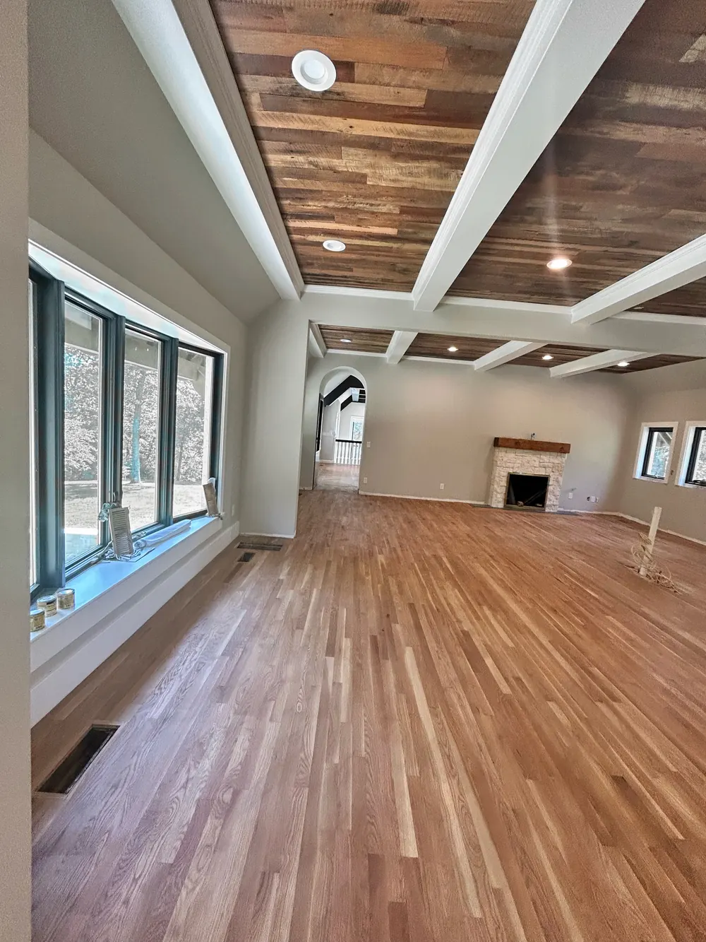 Great room with a natural white oak floor running toward a stone fireplace